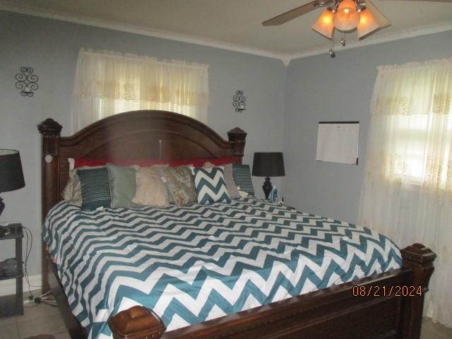 bedroom with ceiling fan and crown molding