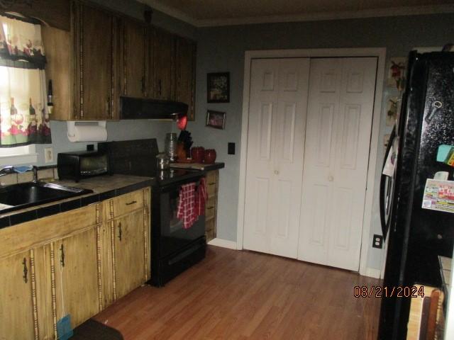 kitchen with black appliances, dark hardwood / wood-style flooring, sink, and extractor fan