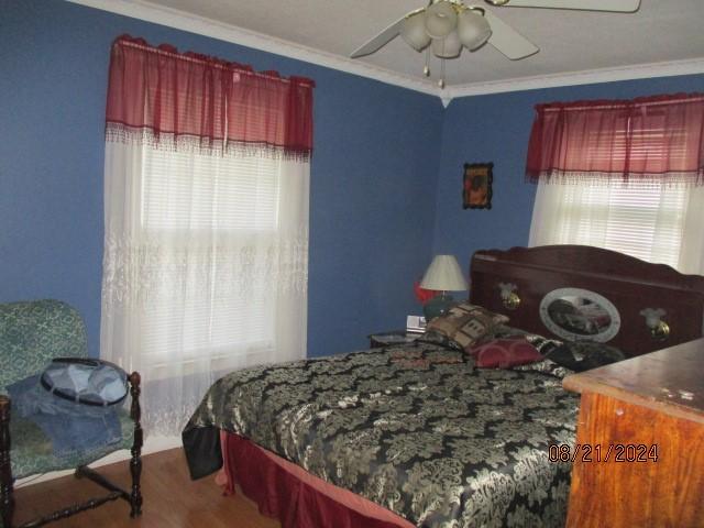 bedroom with ceiling fan, crown molding, and wood-type flooring