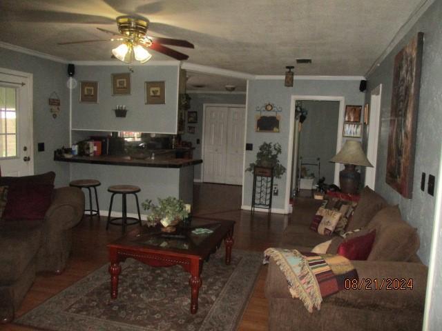 living room featuring ceiling fan, hardwood / wood-style flooring, and ornamental molding