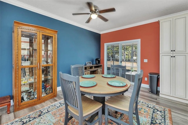 dining room with light wood-style flooring, a ceiling fan, crown molding, and baseboards