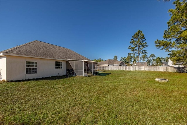 rear view of property featuring fence, a lawn, a sunroom, and stucco siding