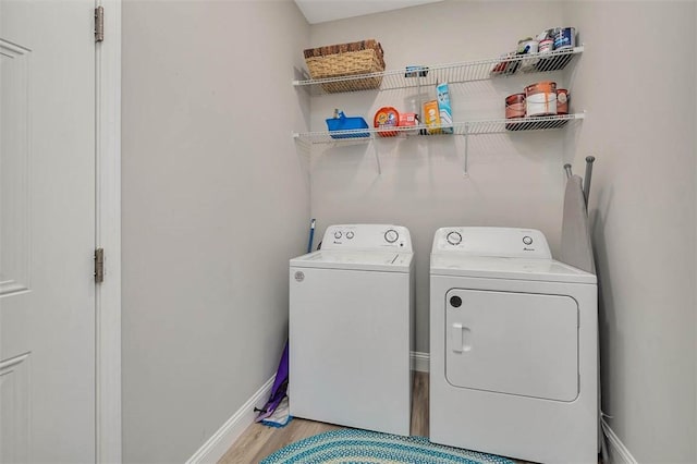 laundry room featuring laundry area, baseboards, light wood finished floors, and washer and clothes dryer