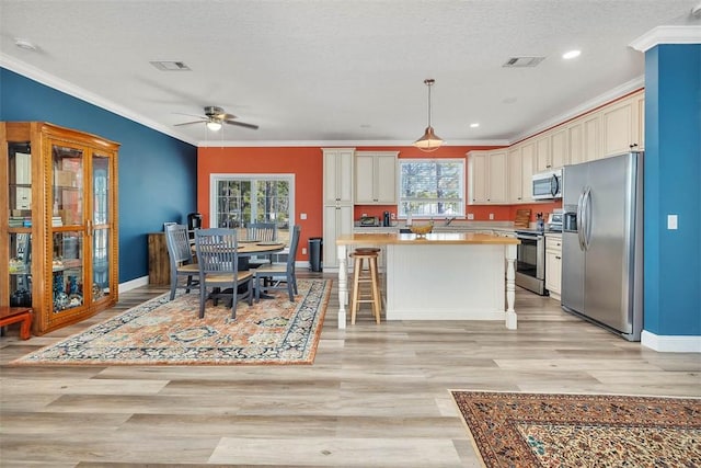 kitchen featuring visible vents, light wood-style flooring, appliances with stainless steel finishes, and crown molding