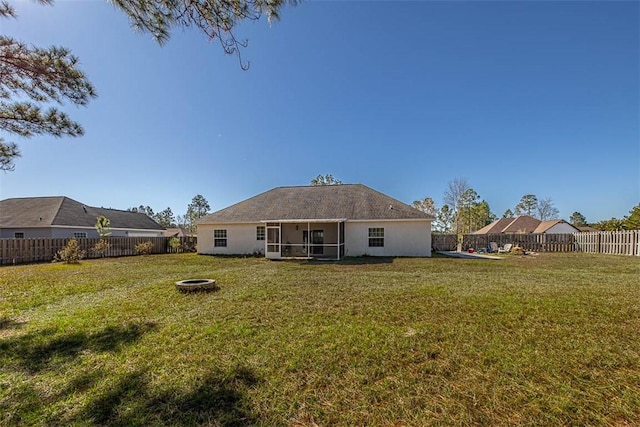 back of property featuring a yard, an outdoor fire pit, a fenced backyard, and a sunroom