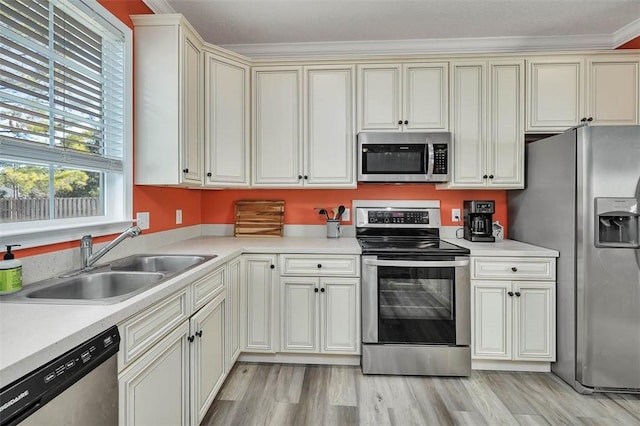 kitchen with light wood-style flooring, a sink, stainless steel appliances, light countertops, and cream cabinetry