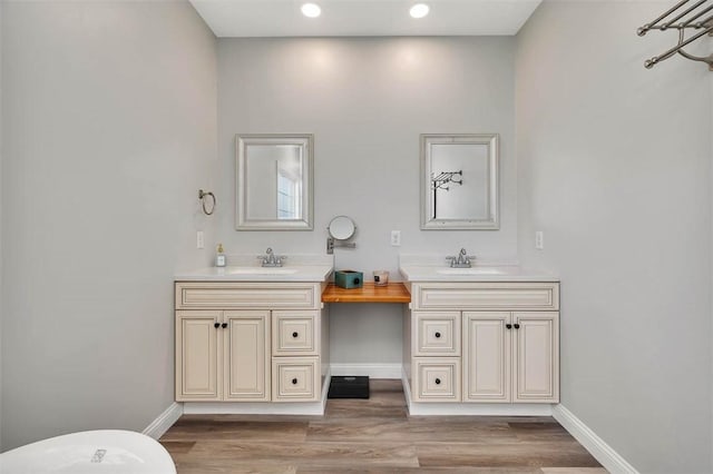 bathroom featuring vanity, recessed lighting, wood finished floors, and baseboards