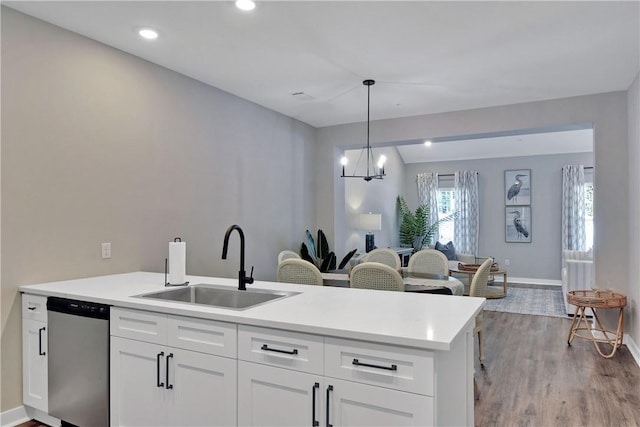 kitchen featuring white cabinets, sink, light hardwood / wood-style flooring, dishwasher, and hanging light fixtures