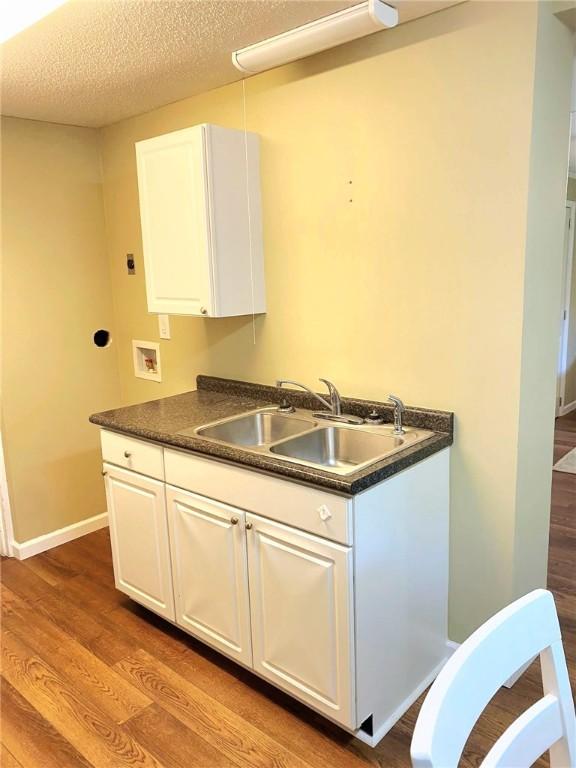 903 Atlantic Ave, Waycross, GA 31501 - kitchen with dark countertops, white cabinets, wood finished floors, and a textured ceiling