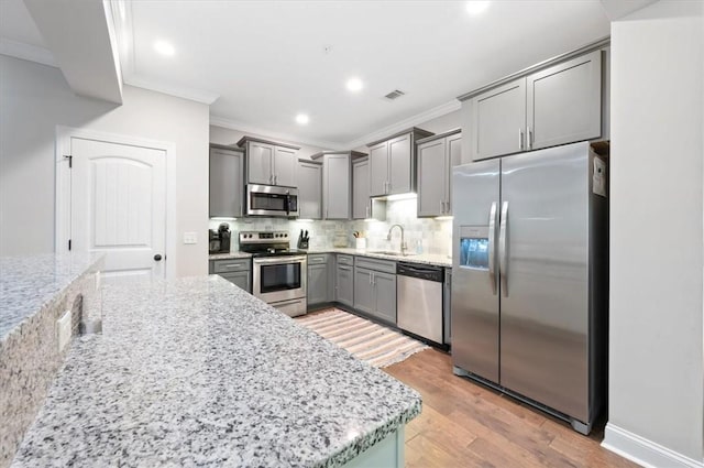 404 Mariners Cir, Saint Simons Island, GA 31522 - kitchen featuring appliances with stainless steel finishes, gray cabinets, crown molding, a sink, and light wood-type flooring