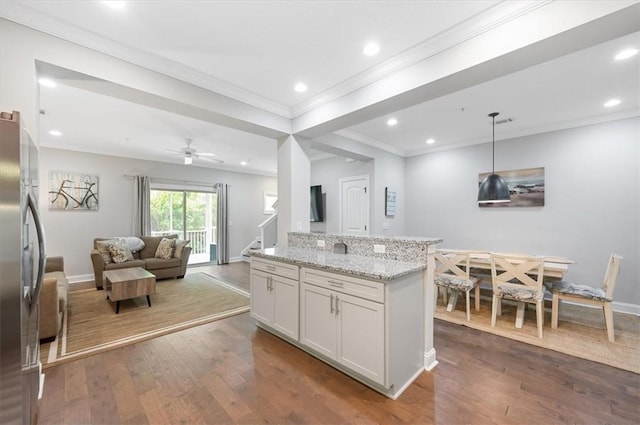 404 Mariners Cir, Saint Simons Island, GA 31522 - kitchen with freestanding refrigerator, dark wood-style flooring, crown molding, light stone countertops, and white cabinetry