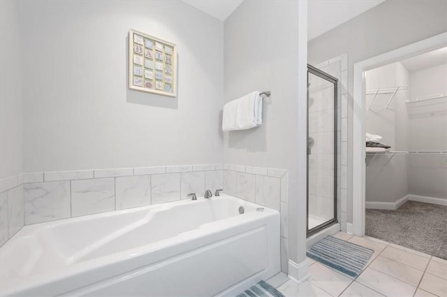 404 Mariners Cir, Saint Simons Island, GA 31522 - bathroom with a stall shower, a garden tub, a walk in closet, and baseboards