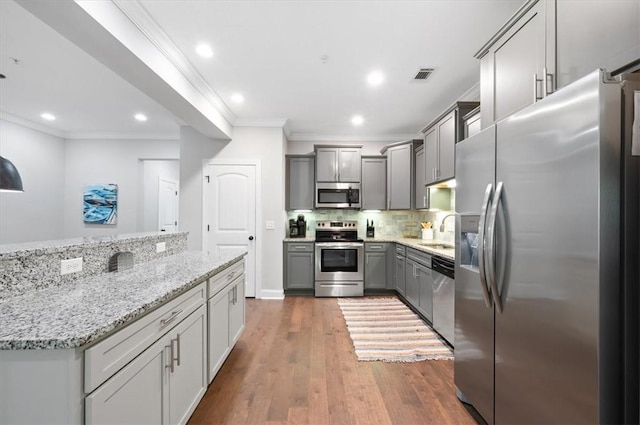 404 Mariners Cir, Saint Simons Island, GA 31522 - kitchen featuring stainless steel appliances, ornamental molding, gray cabinets, light stone countertops, and decorative backsplash