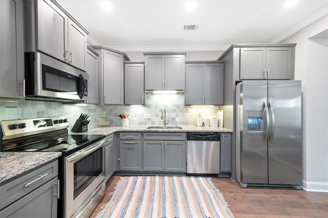 404 Mariners Cir, Saint Simons Island, GA 31522 - kitchen featuring stainless steel appliances, a sink, gray cabinets, crown molding, and light stone counters