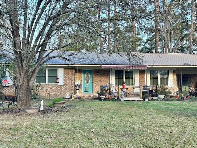 ranch-style house with covered porch, a front lawn, metal roof, and brick siding