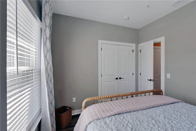 bedroom featuring wood finished floors, visible vents, a closet, and baseboards