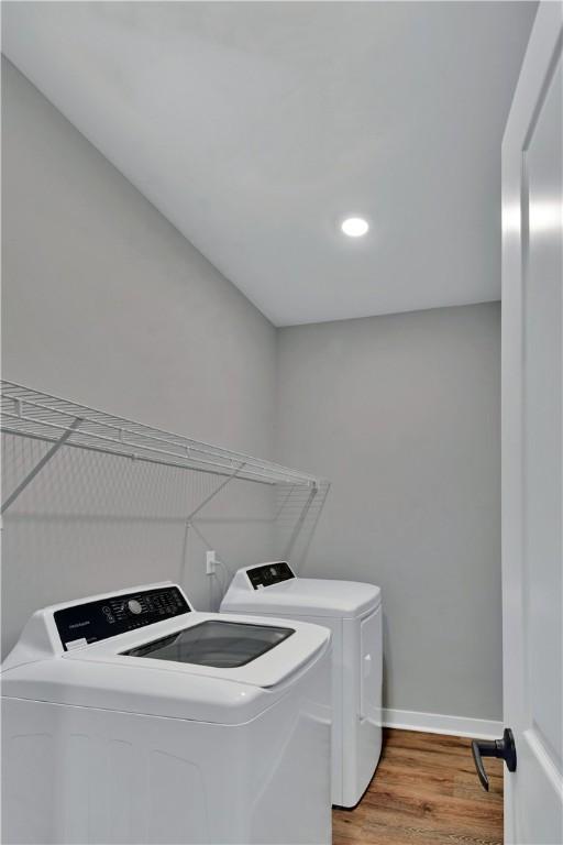 laundry room featuring laundry area, light wood-style flooring, washing machine and dryer, and baseboards