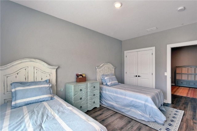 bedroom with wood finished floors, visible vents, a closet, and baseboards