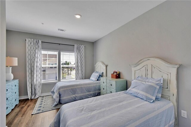 bedroom with visible vents, baseboards, and wood finished floors