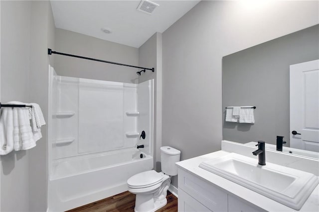 full bath with visible vents, shower / washtub combination, toilet, wood finished floors, and vanity