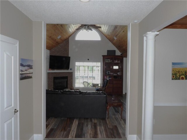 living room featuring ceiling fan, a brick fireplace, dark hardwood / wood-style floors, decorative columns, and lofted ceiling