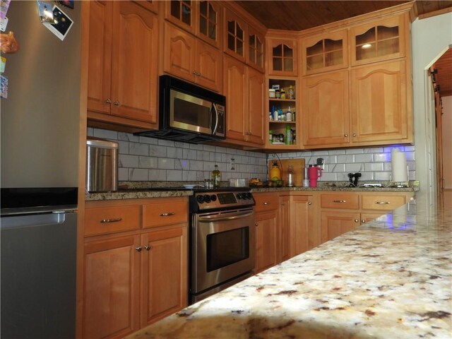 kitchen with backsplash, light stone counters, and stainless steel appliances