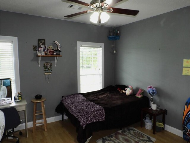 bedroom featuring hardwood / wood-style flooring, multiple windows, and ceiling fan