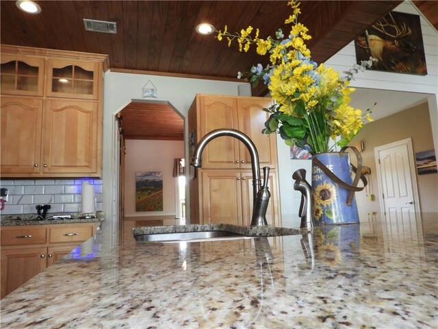 interior details featuring light brown cabinets, backsplash, crown molding, sink, and light stone countertops