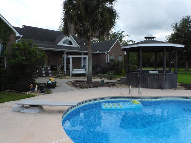 view of pool with a gazebo, a diving board, and a patio