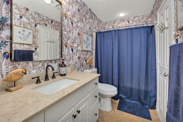 full bathroom featuring tile patterned flooring, a textured ceiling, toilet, shower / bath combo with shower curtain, and vanity