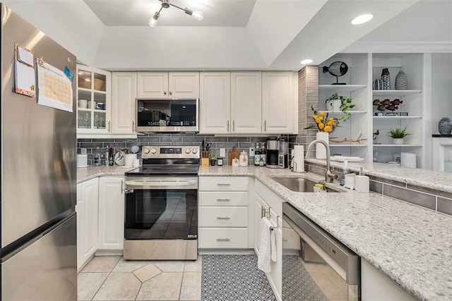 kitchen with backsplash, light stone countertops, sink, and appliances with stainless steel finishes