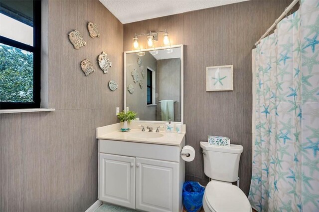 bathroom featuring a shower with curtain, vanity, toilet, and a textured ceiling