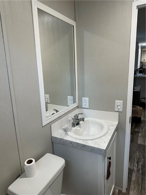 bathroom with toilet, vanity, and wood-type flooring