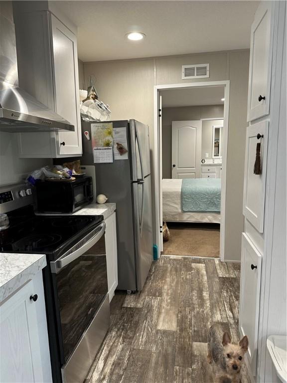 kitchen with white cabinetry, stainless steel range with electric stovetop, dark wood-type flooring, and wall chimney range hood