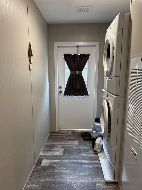 washroom featuring dark hardwood / wood-style floors and stacked washing maching and dryer