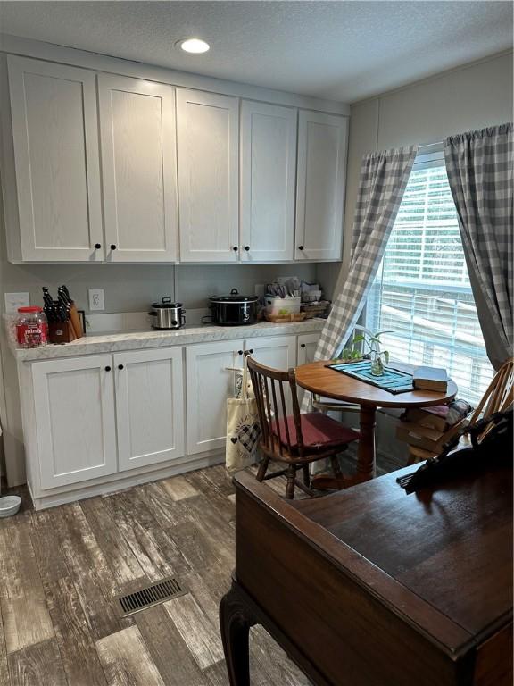 kitchen with light hardwood / wood-style floors, white cabinetry, and a textured ceiling