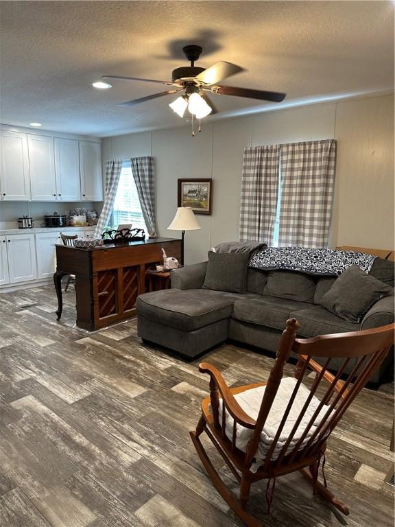 living room featuring hardwood / wood-style floors, ceiling fan, and a textured ceiling