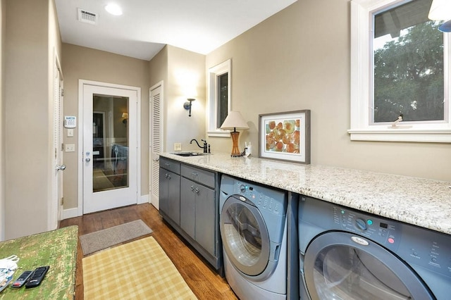 clothes washing area featuring washing machine and clothes dryer, dark hardwood / wood-style flooring, and sink