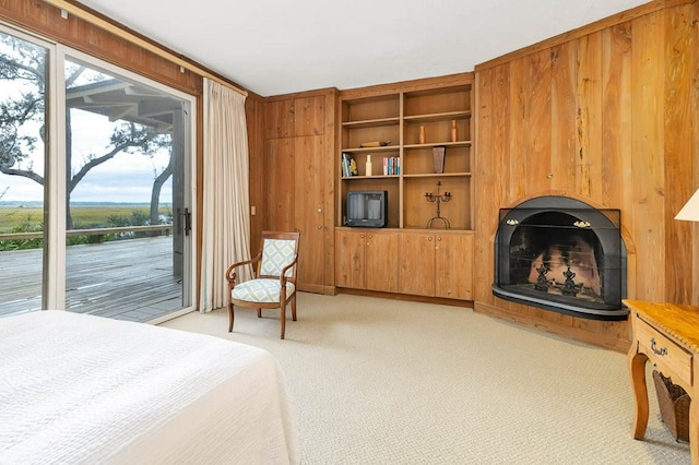 carpeted bedroom with wood walls, multiple windows, and access to outside