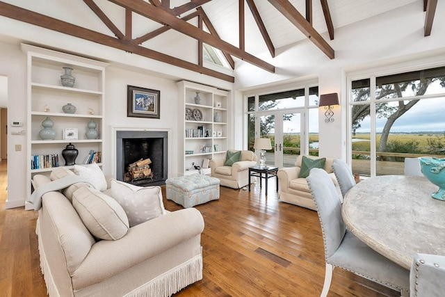 living room with built in features, high vaulted ceiling, wood-type flooring, beam ceiling, and french doors