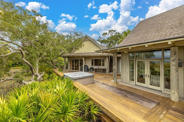 rear view of house with a hot tub, a deck, and french doors