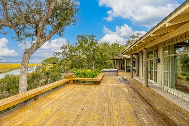 wooden deck featuring a hot tub and a water view