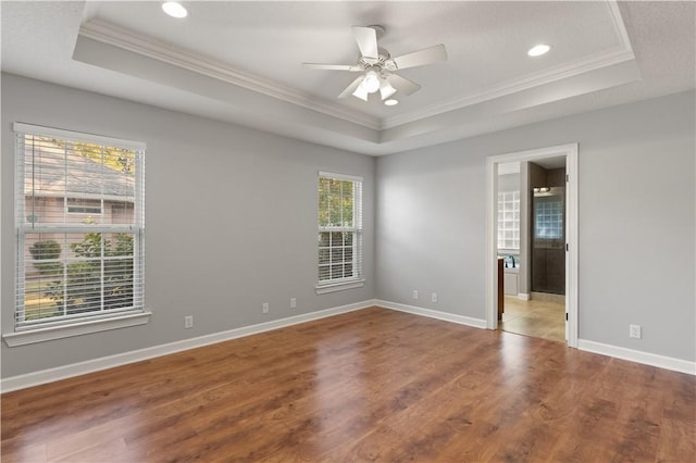 spare room with wood-type flooring, a raised ceiling, and crown molding