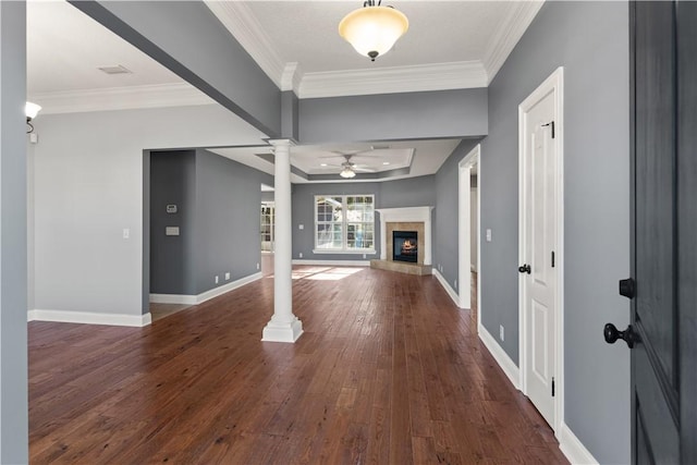 entryway with ornate columns, ceiling fan, dark wood-type flooring, crown molding, and a tray ceiling