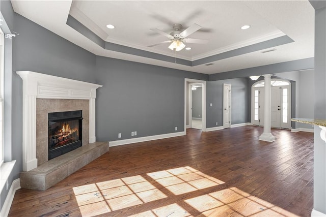 unfurnished living room featuring a raised ceiling, crown molding, hardwood / wood-style flooring, ceiling fan, and a fireplace