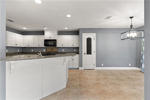 kitchen with dark stone counters, a textured ceiling, an inviting chandelier, white cabinets, and hanging light fixtures