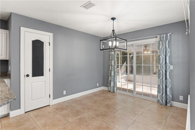 unfurnished dining area with light tile patterned floors, a chandelier, and a textured ceiling