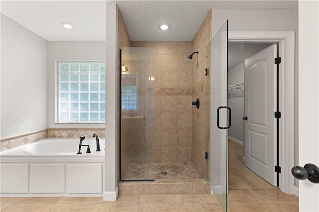 bathroom featuring tile patterned flooring, shower with separate bathtub, and a textured ceiling