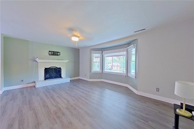 1206 Morningside Dr, Waycross, GA 31501 - unfurnished living room featuring a brick fireplace, wood finished floors, and a ceiling fan