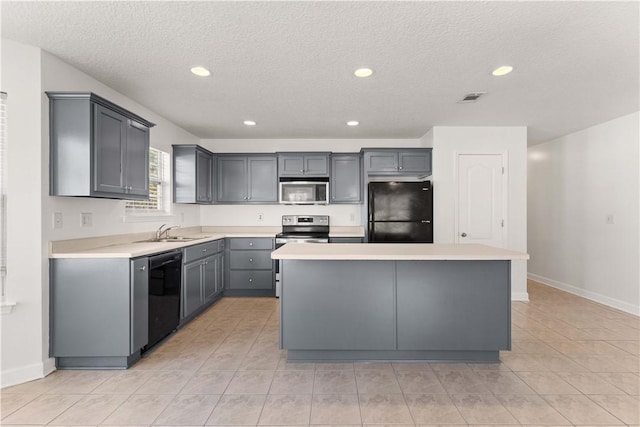 kitchen featuring a center island, light countertops, gray cabinets, black appliances, and a sink